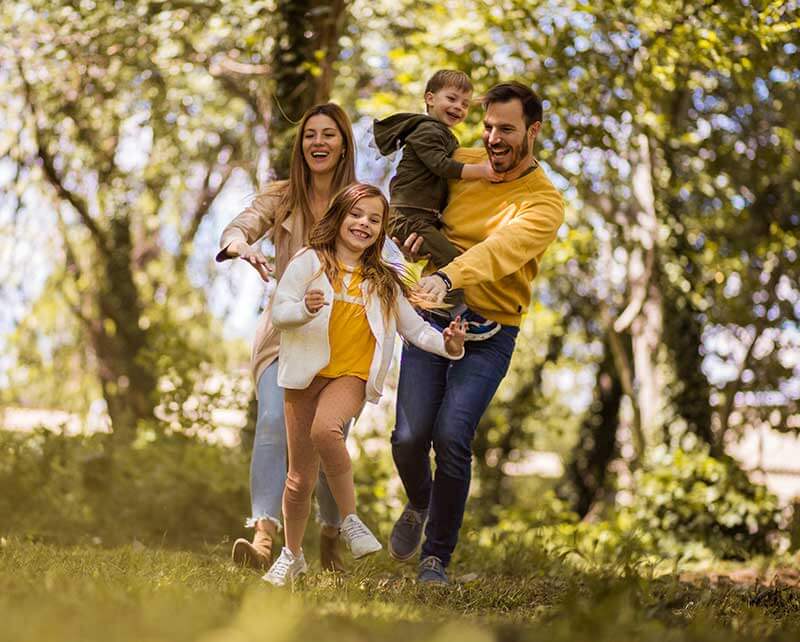 Happy family of four running through a park